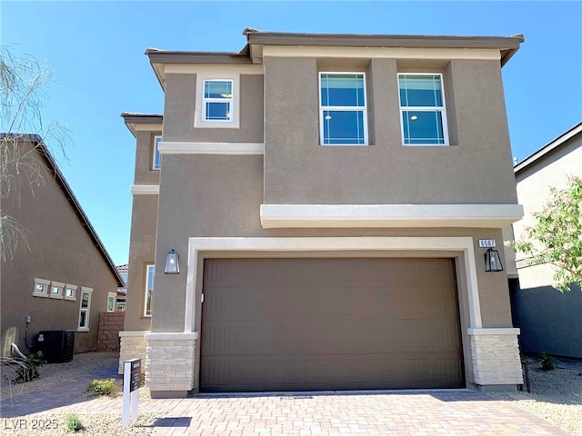 view of front of property featuring stucco siding, stone siding, and an attached garage