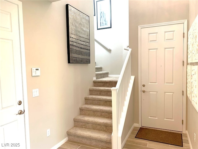 staircase featuring wood finish floors and baseboards