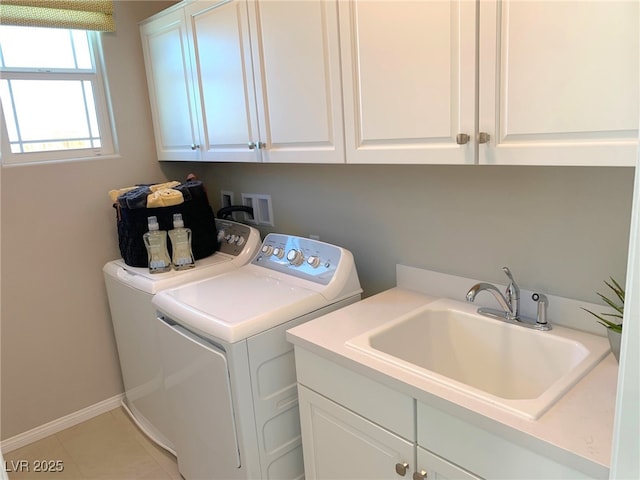 washroom featuring baseboards, light tile patterned flooring, cabinet space, a sink, and washer and dryer