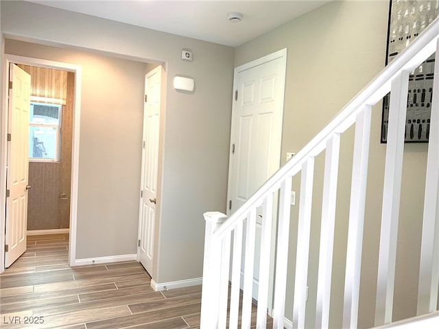 corridor with stairs, baseboards, and wood finish floors