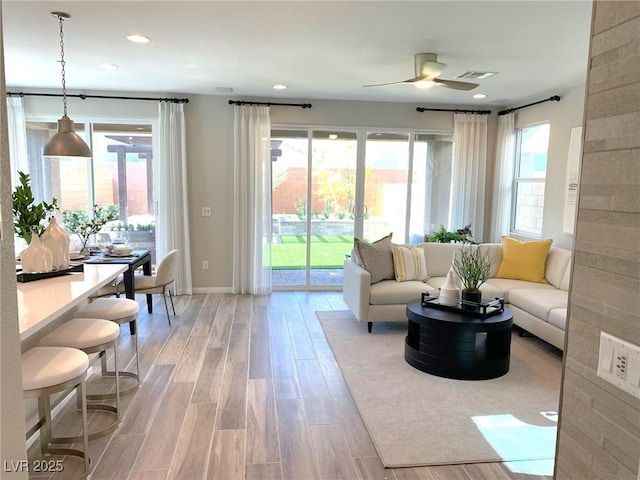 living area with recessed lighting, plenty of natural light, visible vents, and light wood-style floors