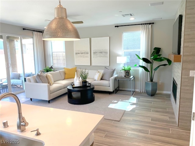 living room with visible vents, baseboards, recessed lighting, a fireplace, and light wood-style floors