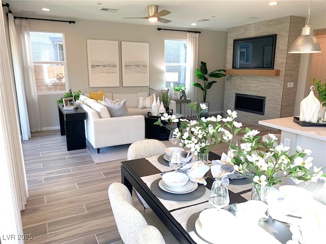 dining space featuring visible vents, wood finish floors, recessed lighting, ceiling fan, and a tiled fireplace