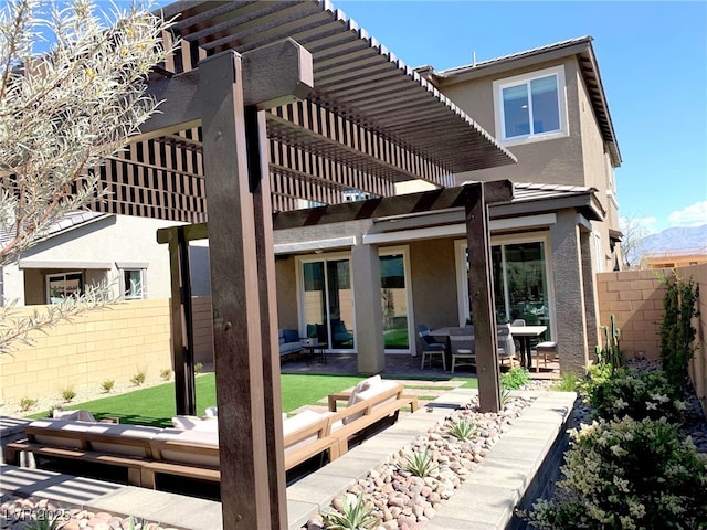 back of property with stucco siding, a pergola, a patio, and fence