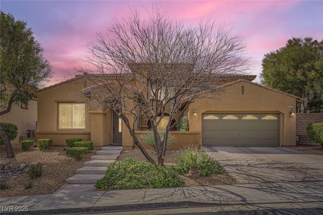 view of front of home with stucco siding, driveway, and an attached garage