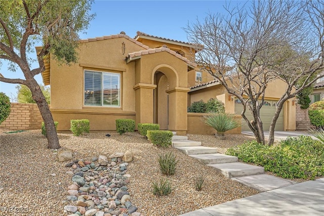 mediterranean / spanish-style house featuring stucco siding, an attached garage, and a tile roof