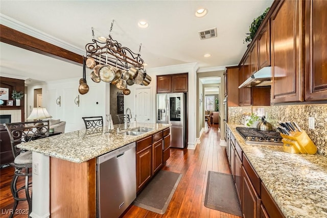 kitchen featuring visible vents, a sink, stainless steel appliances, under cabinet range hood, and crown molding