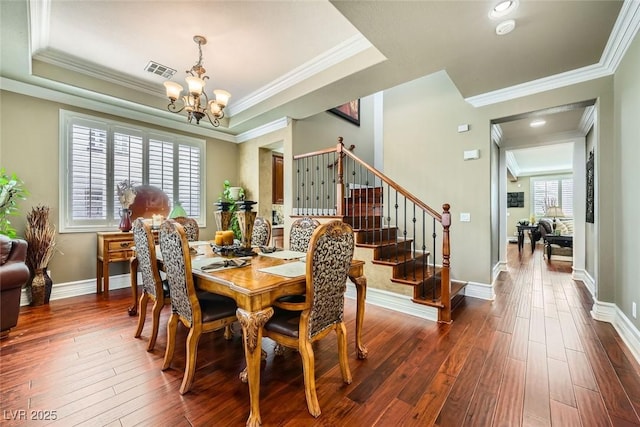 dining space with a tray ceiling, visible vents, dark wood-style flooring, and stairway