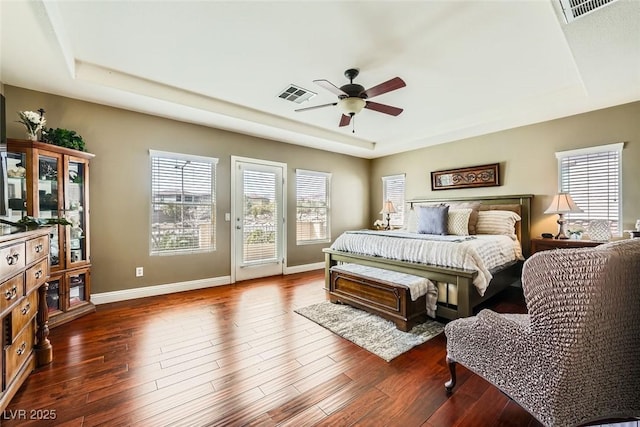 bedroom featuring a raised ceiling, dark wood-style floors, access to exterior, and visible vents