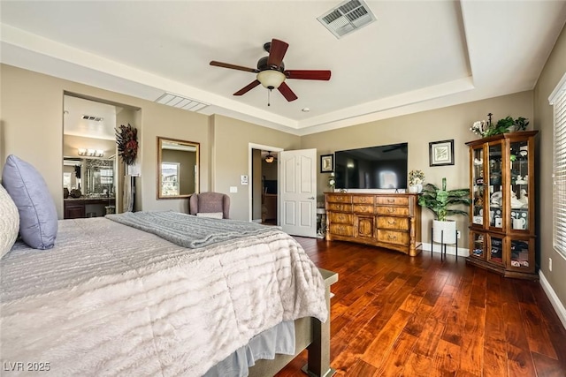 bedroom with visible vents, baseboards, freestanding refrigerator, hardwood / wood-style flooring, and a raised ceiling