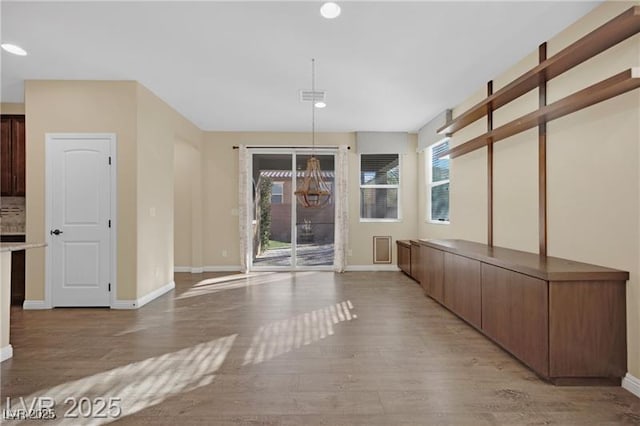 unfurnished dining area with visible vents, baseboards, and light wood-type flooring