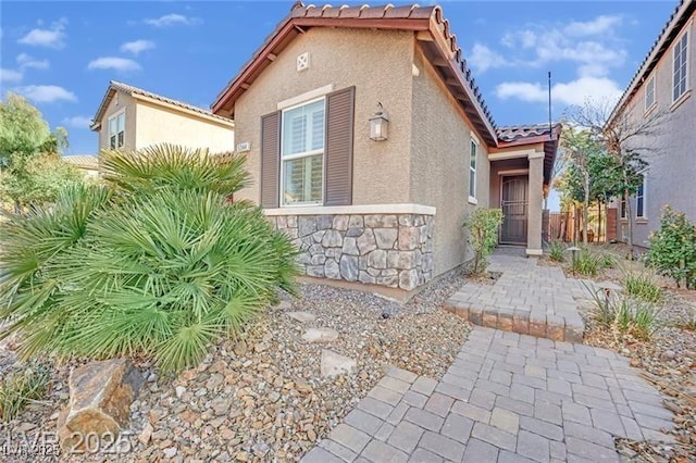 view of front of house featuring stucco siding, stone siding, and a tiled roof