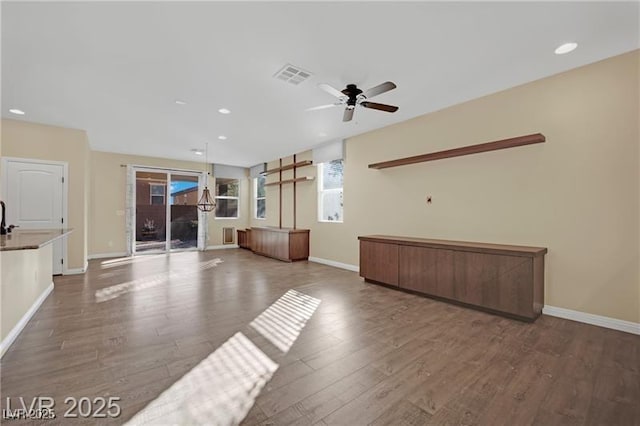 unfurnished living room with wood finished floors, visible vents, and baseboards