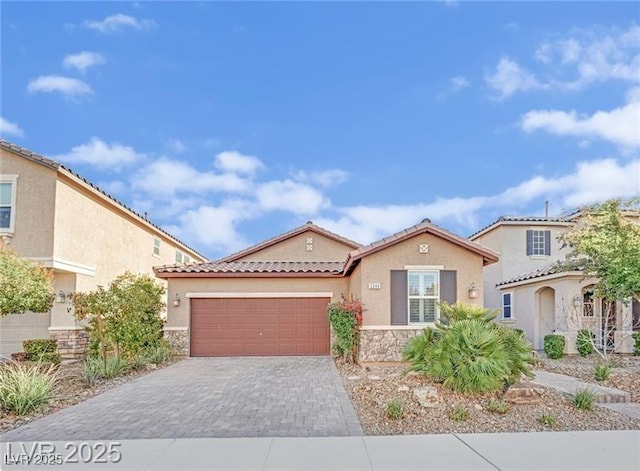 mediterranean / spanish house with decorative driveway, stone siding, an attached garage, and stucco siding