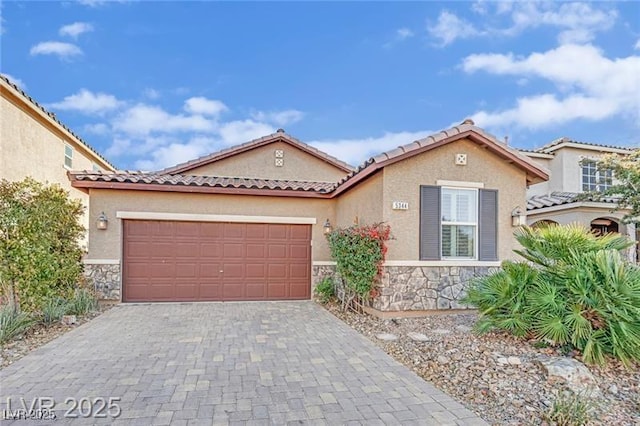 mediterranean / spanish home featuring decorative driveway, stone siding, and stucco siding