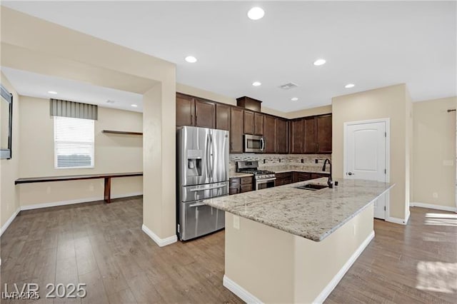 kitchen featuring dark brown cabinetry, stainless steel appliances, light wood-style floors, and a sink