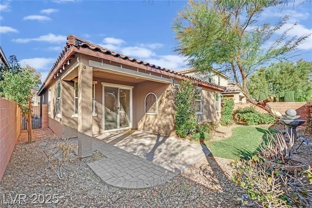 rear view of house with a patio, a tiled roof, a fenced backyard, and stucco siding