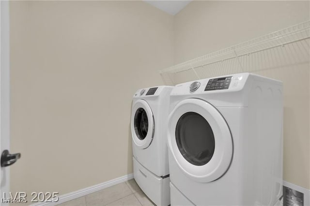 laundry area with baseboards, independent washer and dryer, light tile patterned flooring, and laundry area