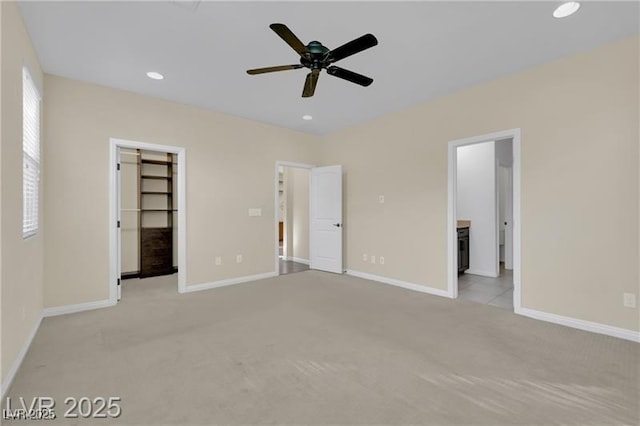 unfurnished bedroom with a spacious closet, recessed lighting, light colored carpet, and baseboards