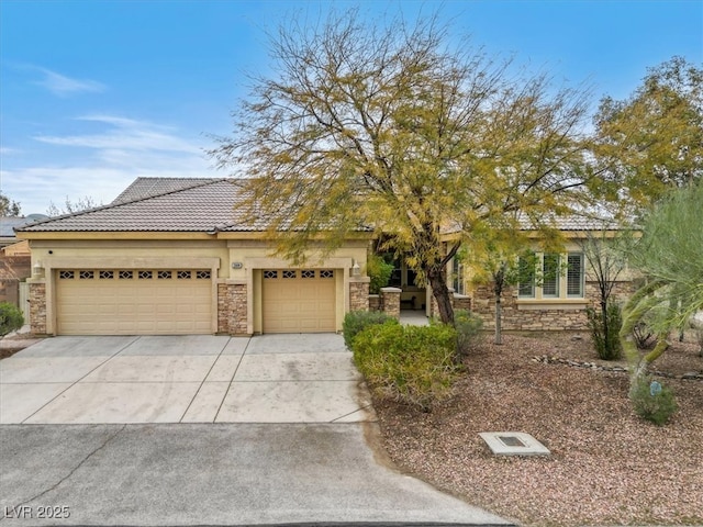 view of front of property featuring stone siding, an attached garage, driveway, and a tiled roof