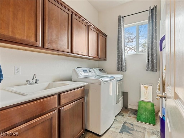 clothes washing area featuring washing machine and dryer, cabinet space, baseboards, and a sink