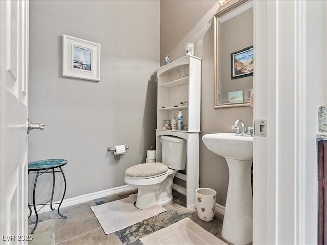 half bath with a sink, baseboards, and toilet