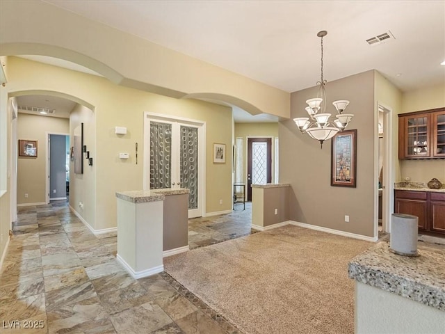 kitchen with baseboards, visible vents, arched walkways, and pendant lighting