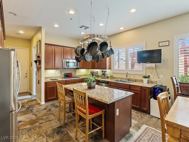 kitchen featuring visible vents, a center island, a breakfast bar area, appliances with stainless steel finishes, and a sink