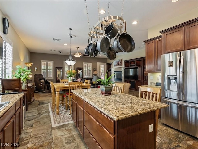 kitchen featuring visible vents, a kitchen island, stainless steel fridge with ice dispenser, open floor plan, and recessed lighting