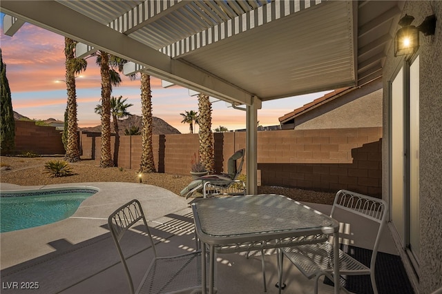 view of patio featuring a fenced in pool, a fenced backyard, outdoor dining space, and a pergola