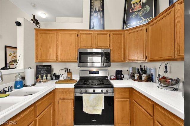 kitchen featuring tile countertops, appliances with stainless steel finishes, and a sink