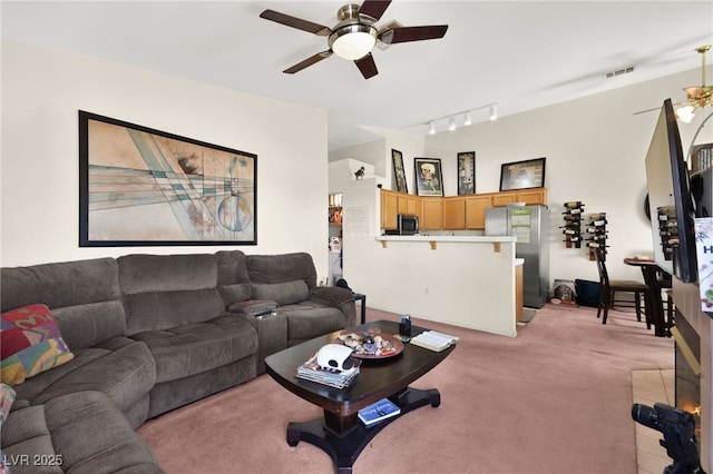 living room featuring track lighting, light colored carpet, visible vents, and a ceiling fan