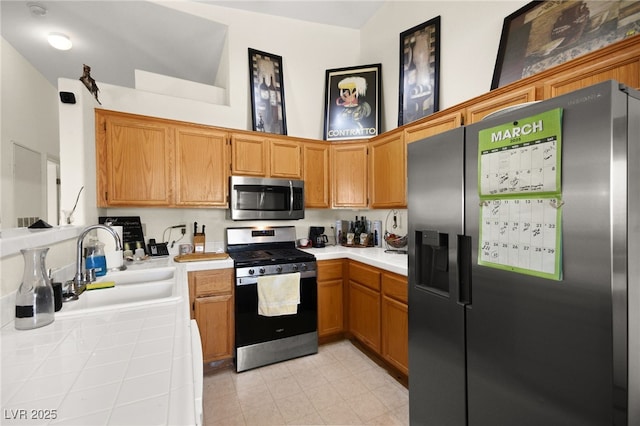 kitchen with a sink, appliances with stainless steel finishes, a towering ceiling, and tile counters