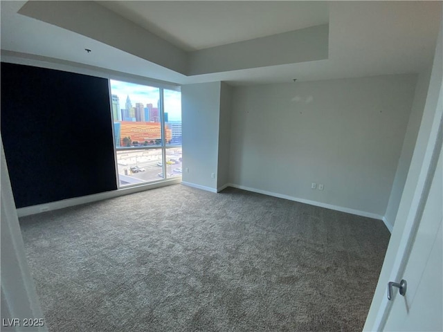 carpeted empty room with a view of city and baseboards