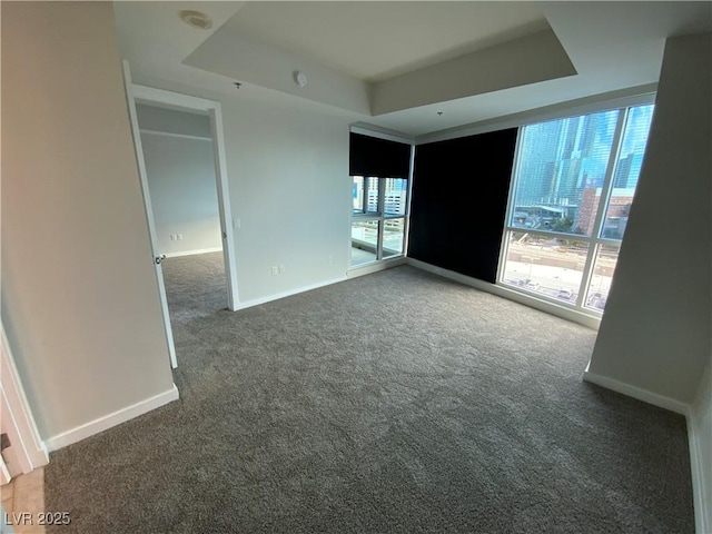 spare room featuring a tray ceiling, baseboards, and carpet floors