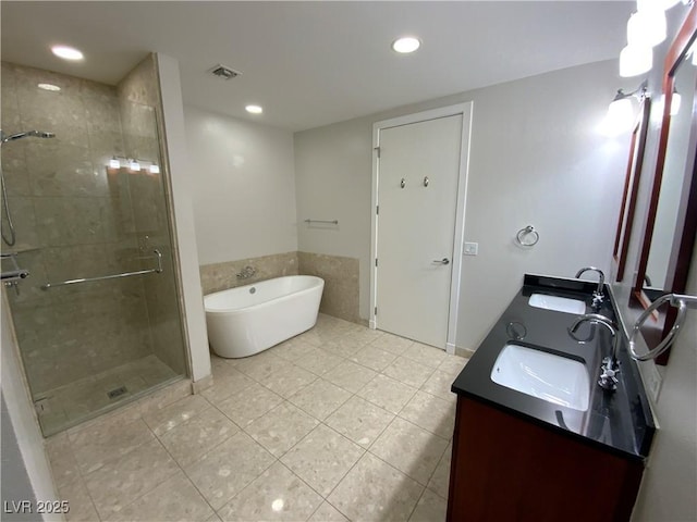 full bathroom featuring double vanity, visible vents, a freestanding bath, and a sink