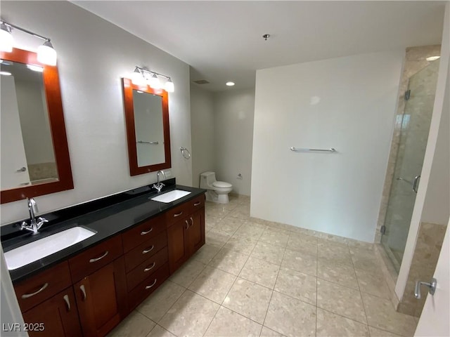 bathroom featuring double vanity, toilet, a stall shower, and a sink