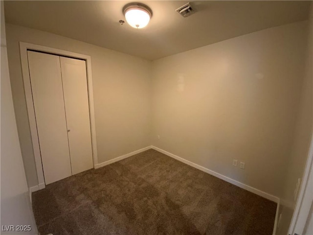 unfurnished bedroom with visible vents, baseboards, a closet, and dark carpet