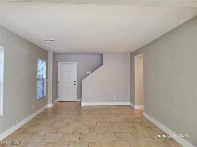 empty room with light tile patterned flooring, visible vents, and baseboards