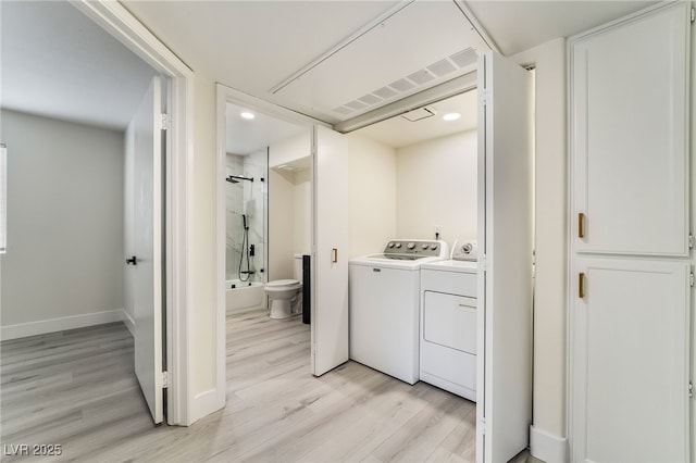 washroom featuring laundry area, light wood-style flooring, baseboards, and washing machine and clothes dryer