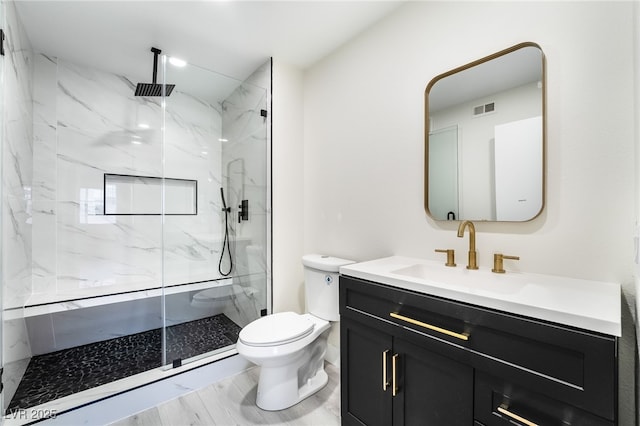 full bath featuring a marble finish shower, visible vents, toilet, and vanity