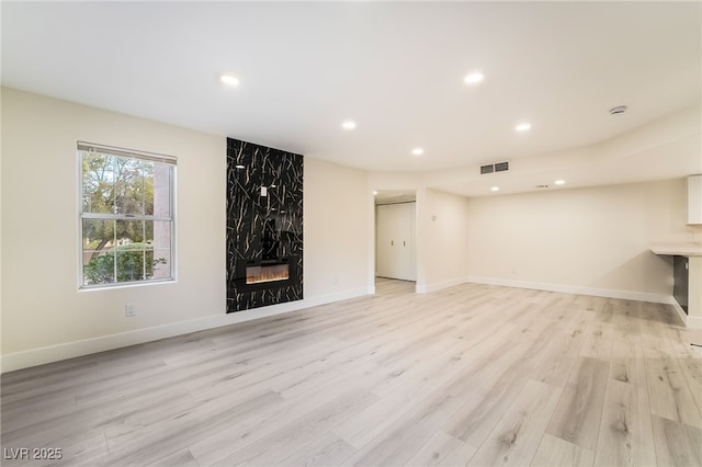 unfurnished living room featuring visible vents, recessed lighting, a fireplace, and light wood-type flooring