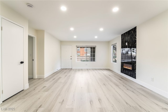 unfurnished living room with light wood-style flooring, recessed lighting, baseboards, and a large fireplace