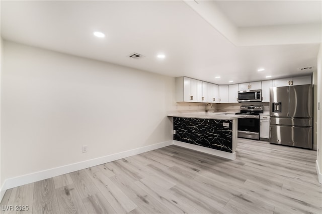 kitchen with stainless steel appliances, baseboards, light wood-style flooring, and light countertops