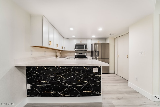 kitchen with a sink, a peninsula, light countertops, and stainless steel appliances