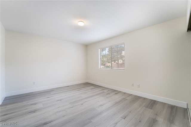 spare room with baseboards and light wood-style floors