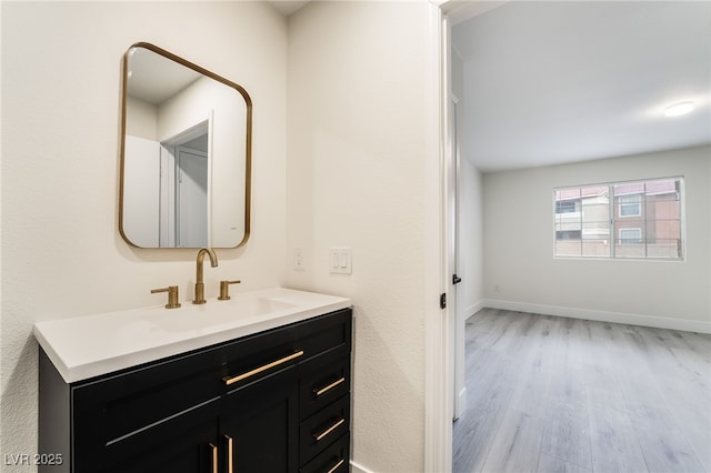 bathroom with baseboards, wood finished floors, and vanity