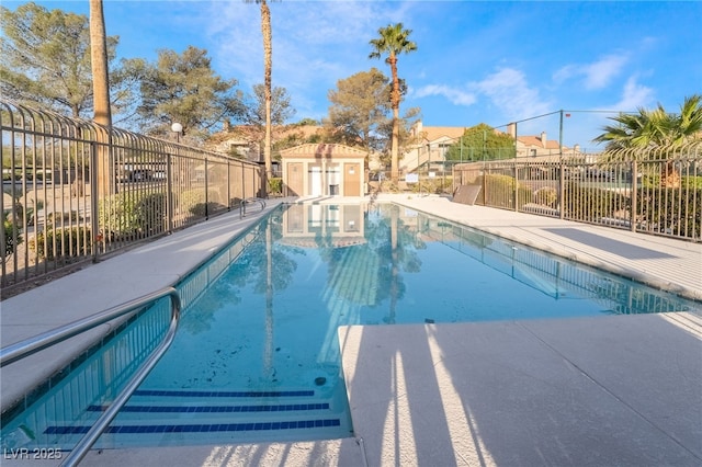 community pool featuring a patio area, an outdoor structure, and fence