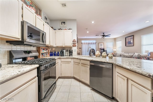 kitchen with a sink, backsplash, open floor plan, stainless steel appliances, and light tile patterned floors