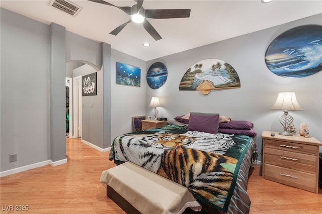 bedroom featuring arched walkways, visible vents, light wood-type flooring, and baseboards